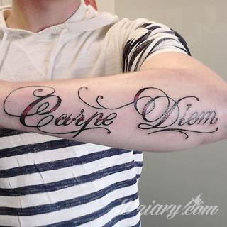 Popularne grafiki z symbolicznym hasłem Carpe Diem - tatuaże o niebanalnej różnorodności czcionek. Carpe Diem na skórze nie musi ograniczać się wyłącznie do standardowej kursywy; intrygować może też hasło w innych formach.