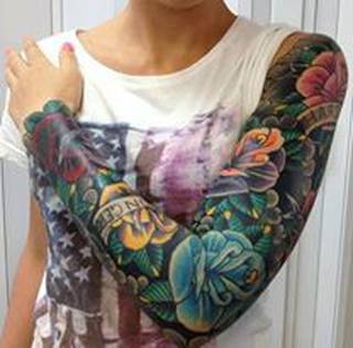 Bardzo kolorowy tatuaż na ręce. Kwiaty, zieleń i napis