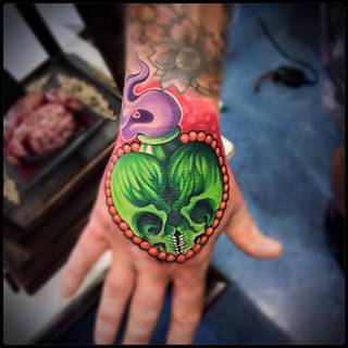 Butelka z trucizną i dwoma czaszkami na zewnętrznej części dłoni.