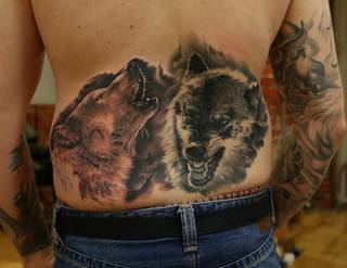 Dwa wściekłe wilki wytatuowane na niskiej części pleców.
