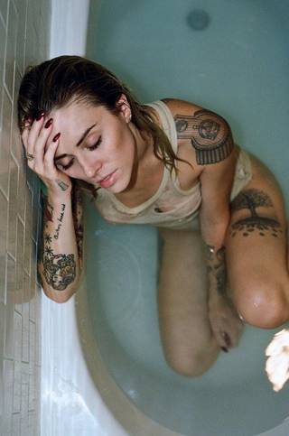 Kobieta z licznymi ciekawymi tatuażami w wannie.