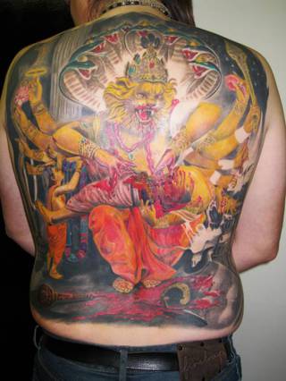 Kolorowy tatuaż indyjskiego boga Nrasimhy jedzącego złożoną mu ofiarę.