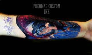 Kosmiczny, abstrakcyjny tatuaż oka na przedramieniu.