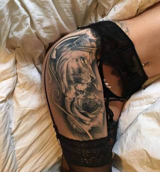 realistycznie oddany tatuaż lwa i róży na kobiecym udzie