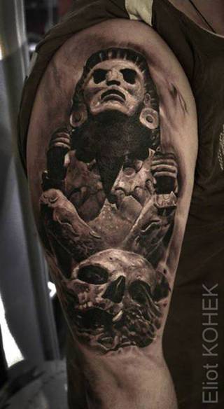 Tatuaż czaszki i azteckiego motywu statuy.