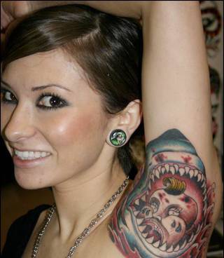 Tatuaż paszczy rekina z postacią w środku pod pachą.