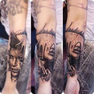 Tatuaż z kobiecymi twarzami na ramieniu.