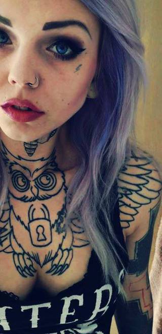 Tatuaże + kolczyk w nosie. Na szyi sowa z kłódką
