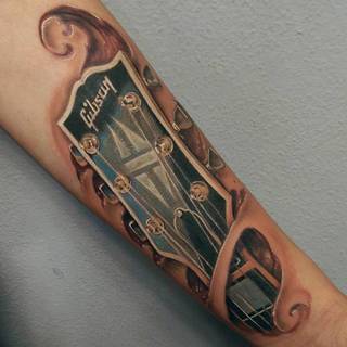 Wydziarana główka gitary na przedramieniu.