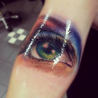 Zielone oko wytatuowane na ręce.